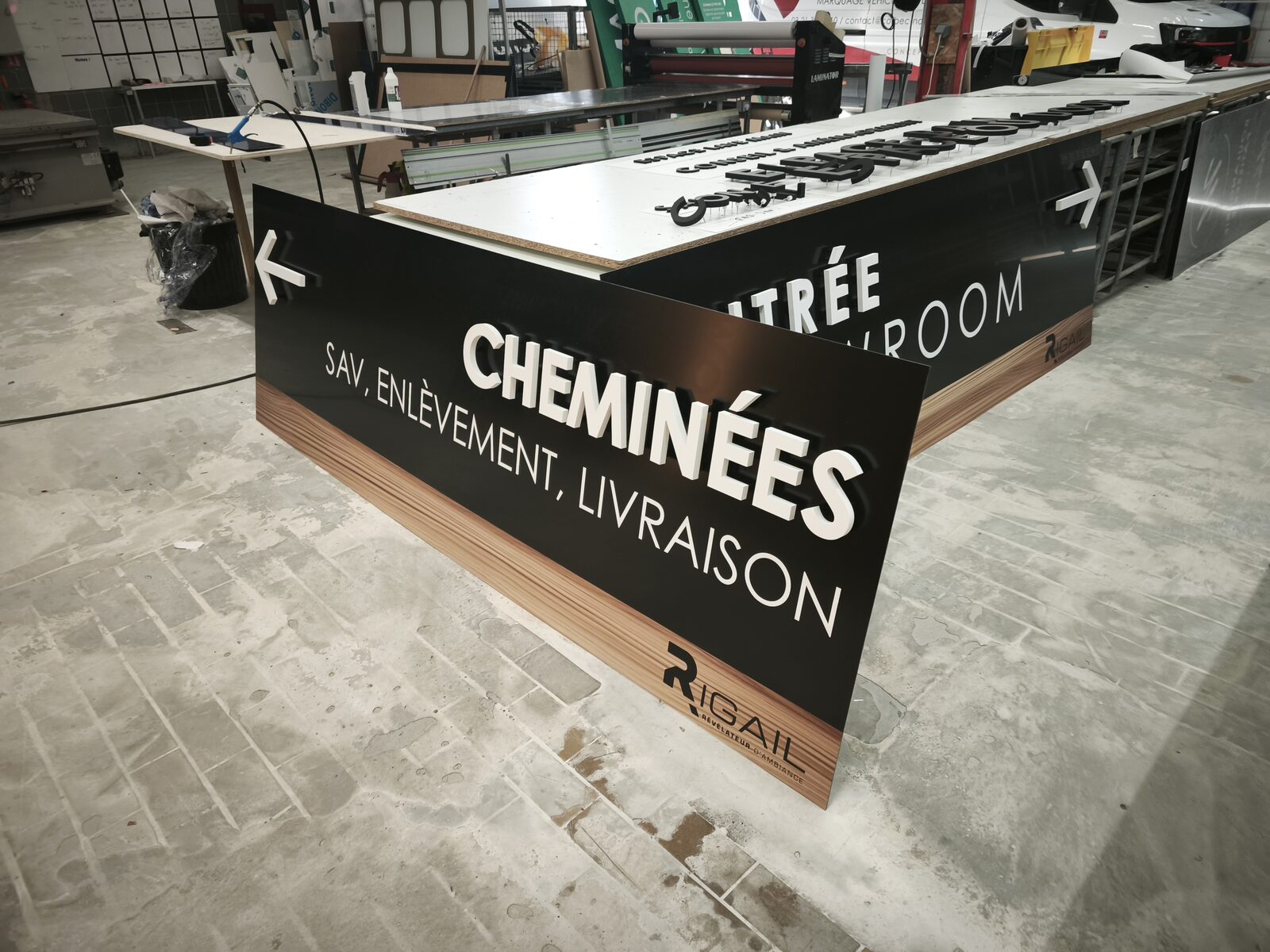 Panneau directionnel Rigail « Cheminées — SAV, enlèvement, livraison » en finition à l'atelier